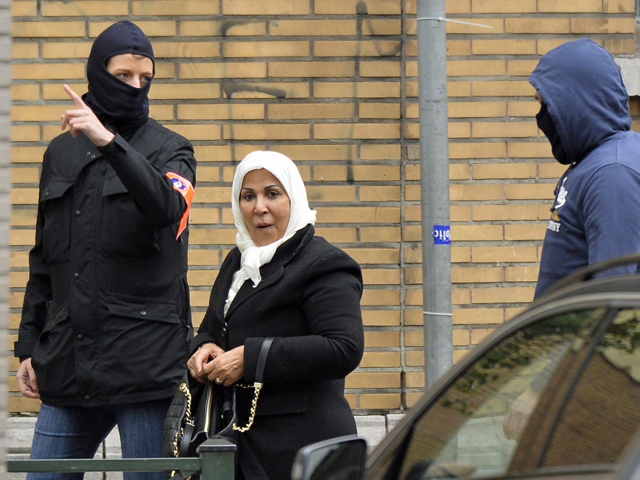 Police escort a woman away from the scene as an operation takes place in the Molenbeek district of Brussels on 16 November, 2015