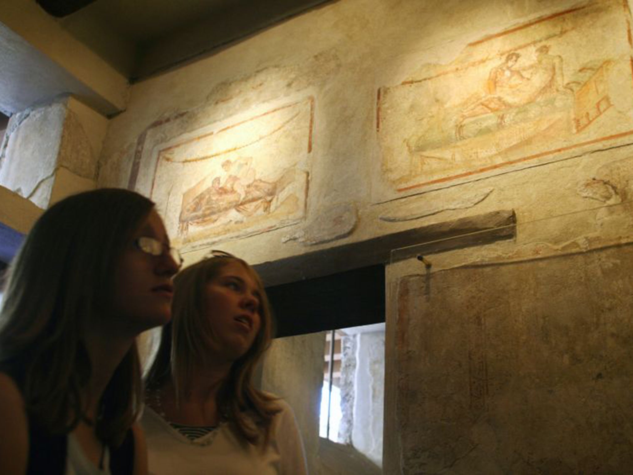 Tourists look over erotic frescoes in Pompeií. Art officials have recently restored an ancient brothel, believed to have been the city's most popular