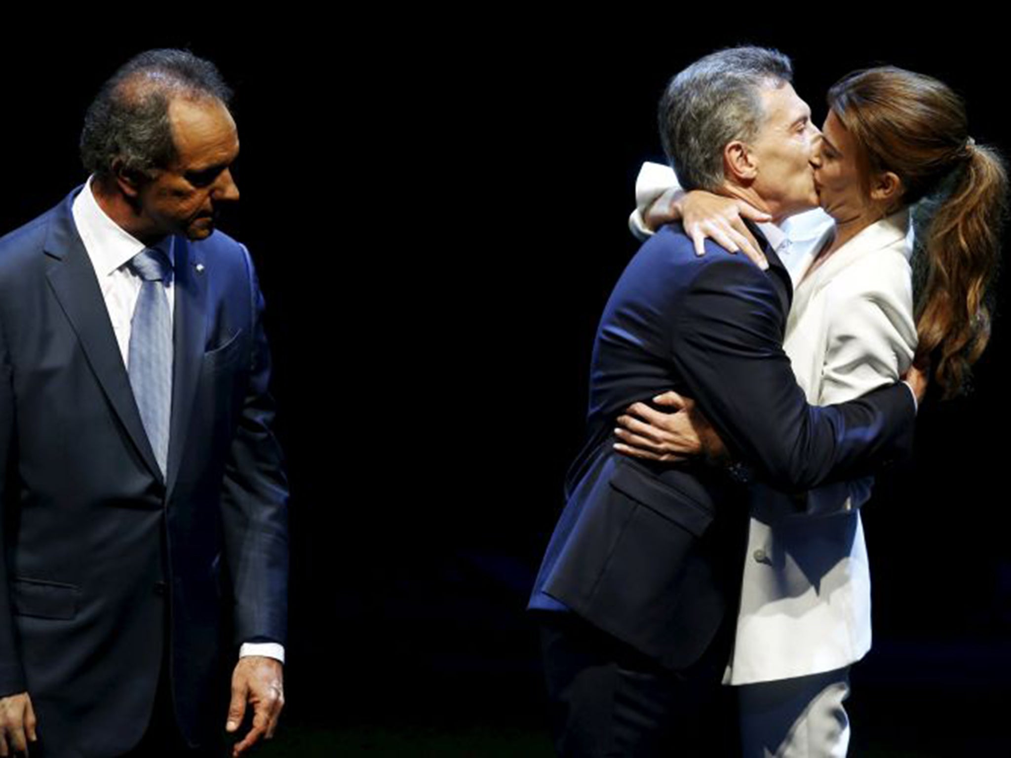 Mauricio Macri kisses his wife as Daniel Scioli looks on at the end of the TV debate