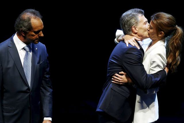 Mauricio Macri kisses his wife as Daniel Scioli looks on at the end of the TV debate
