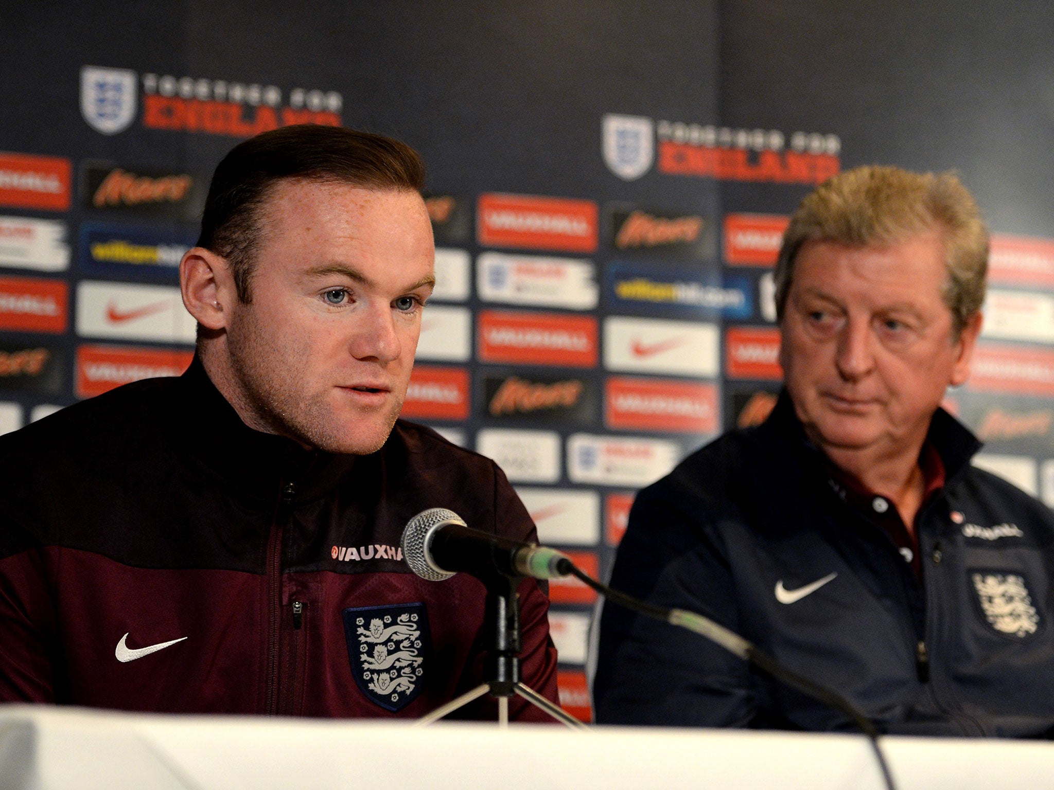 England captain Wayne Rooney speaks to the media as manager Roy Hodgson looks on