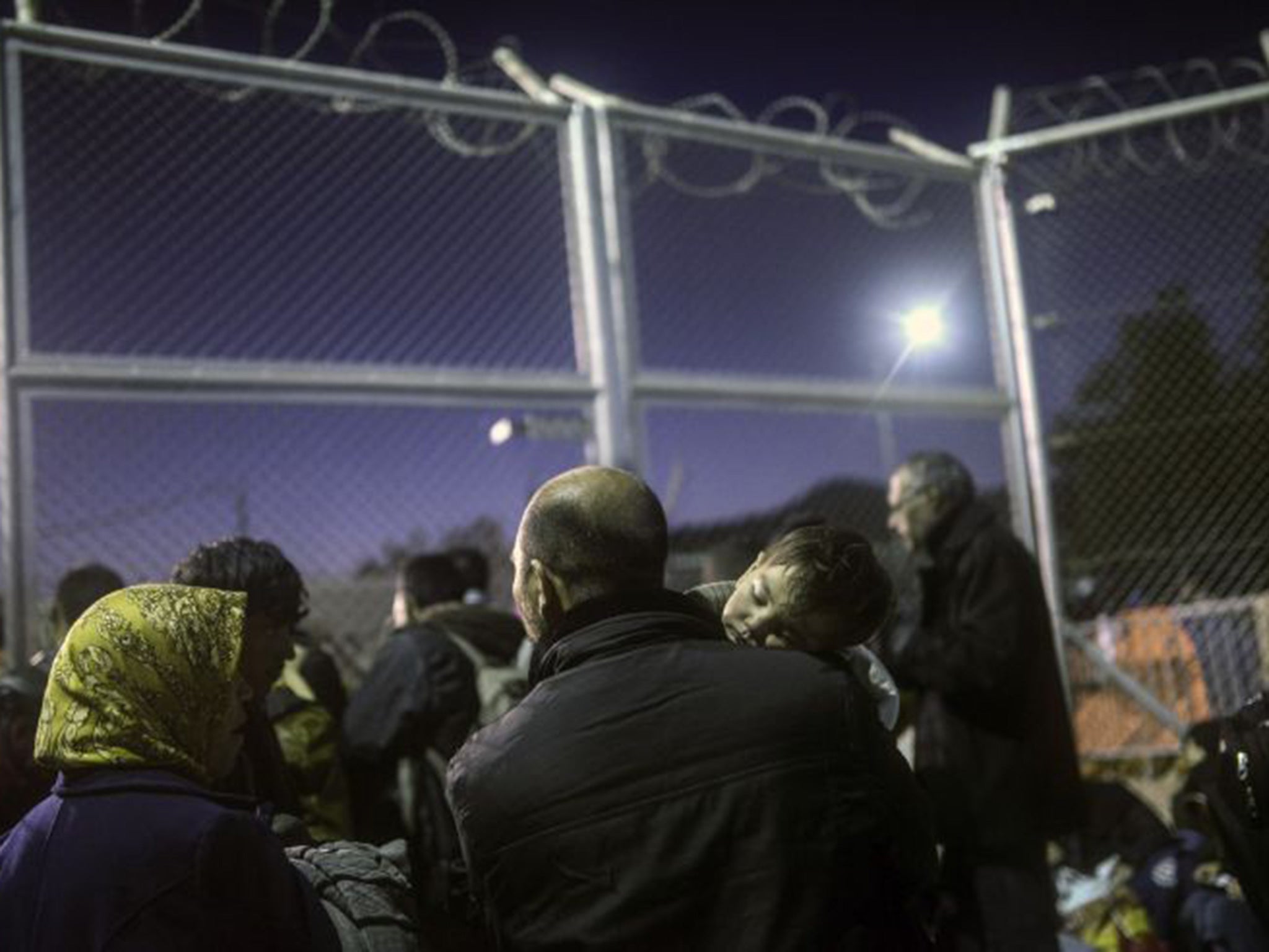 Refugees and migrants wait in front of a gate for registration in an a camp on the Greek island of Lesbos