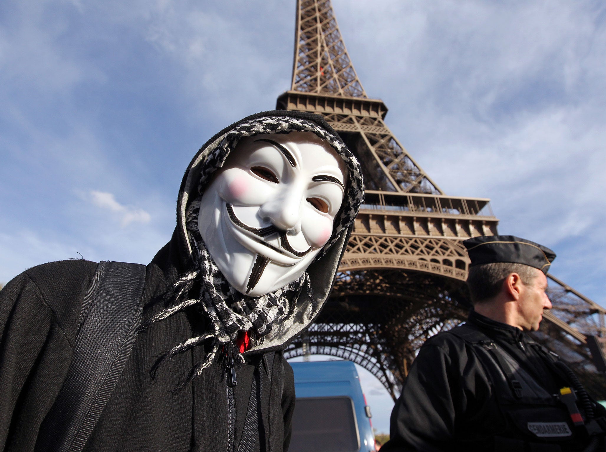 A protester wearing an Anonymous Guy Fawkes mask takes part in a demonstration in front of the Eiffel tower in Paris