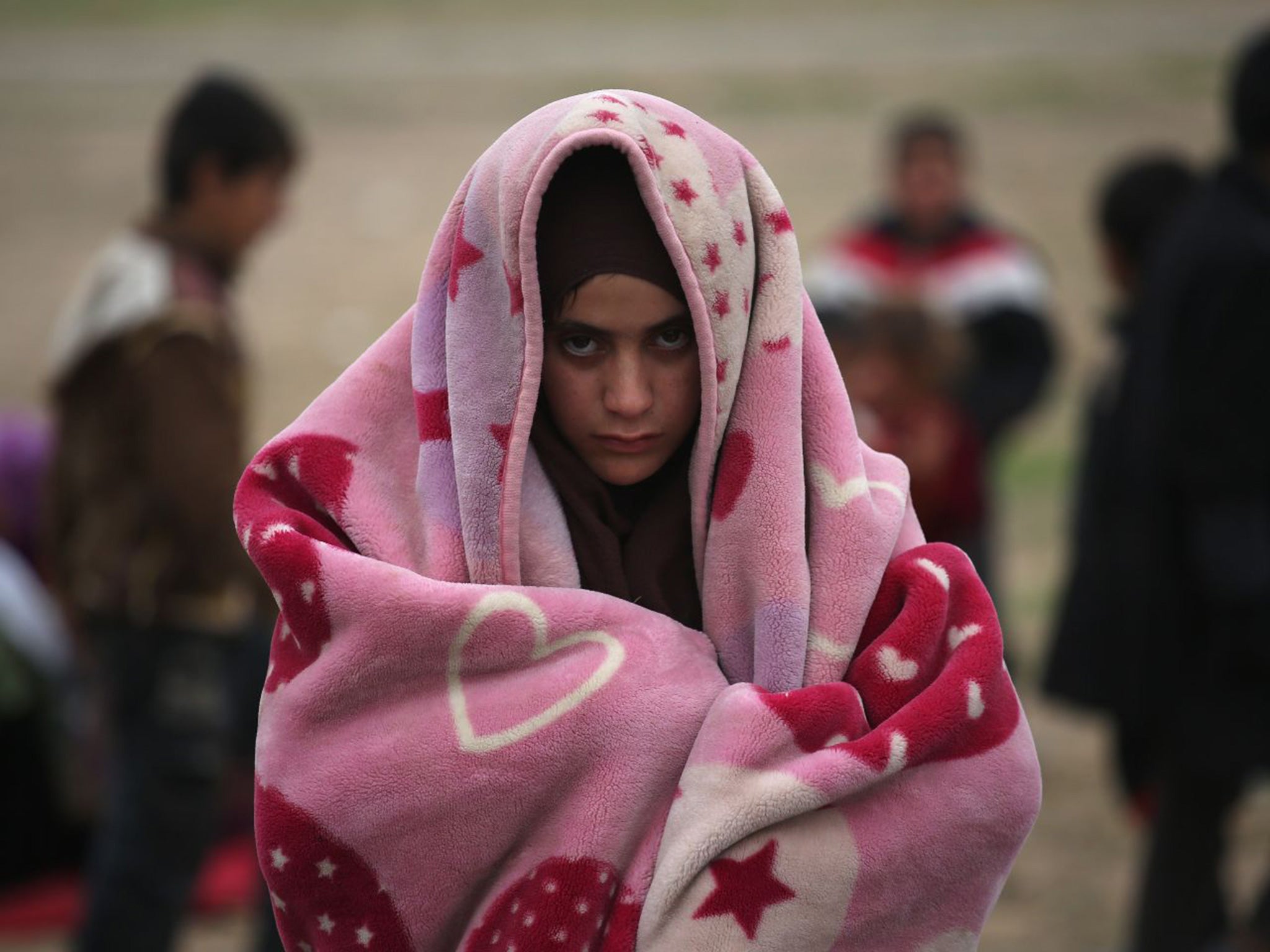 A girl bundles against the cold while fleeing the Isis frontline in Syria