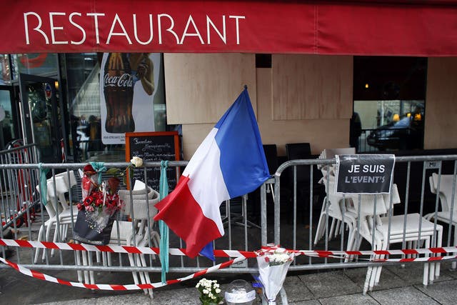 The French flag and floral tributes are displayed on a barrier near a restaurant hit by the terror attacks near the Stade De France stadium in Saint-Denis