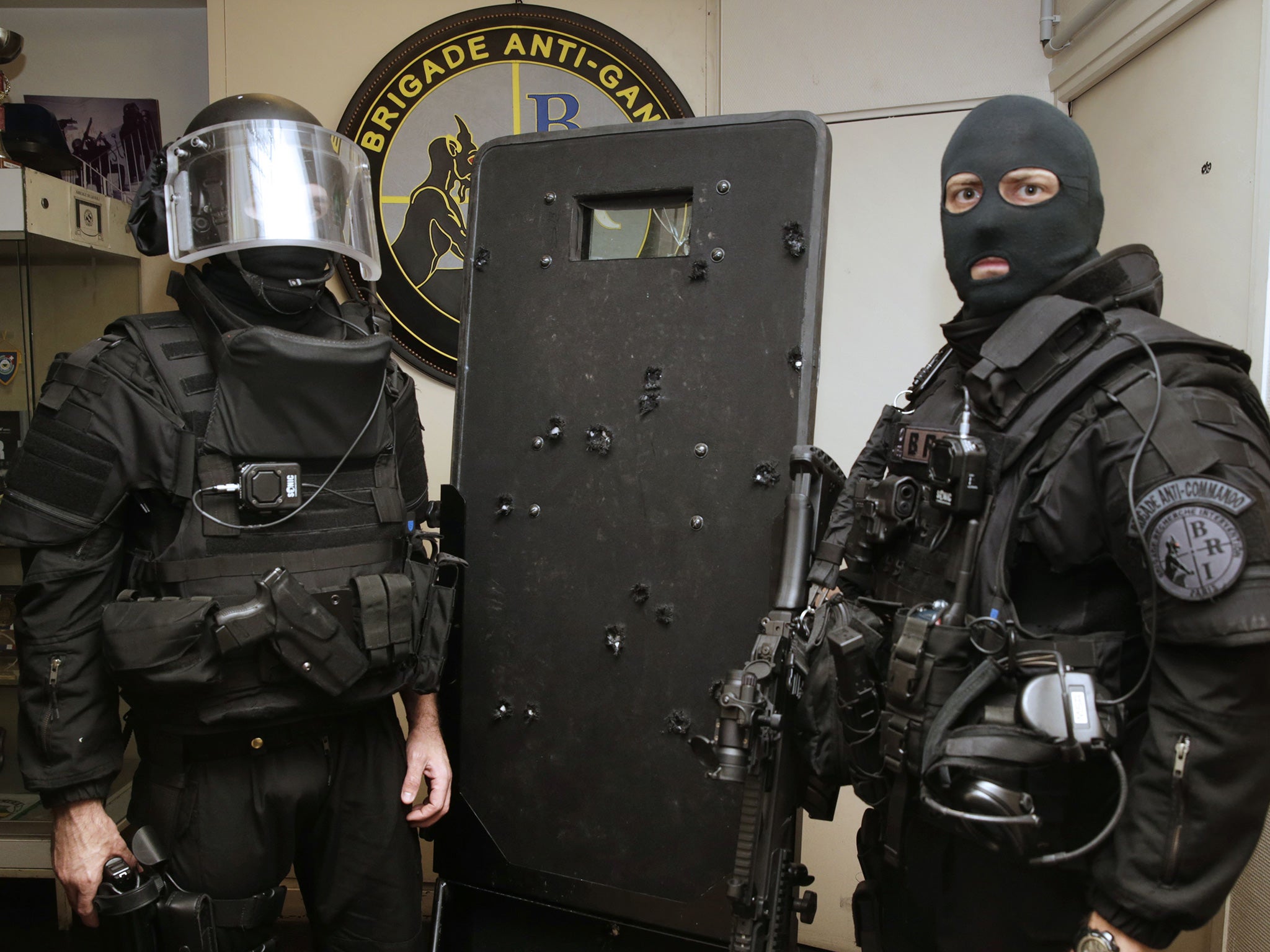 Police commandos pose with a bullet-riddled riot shield, used in the assault