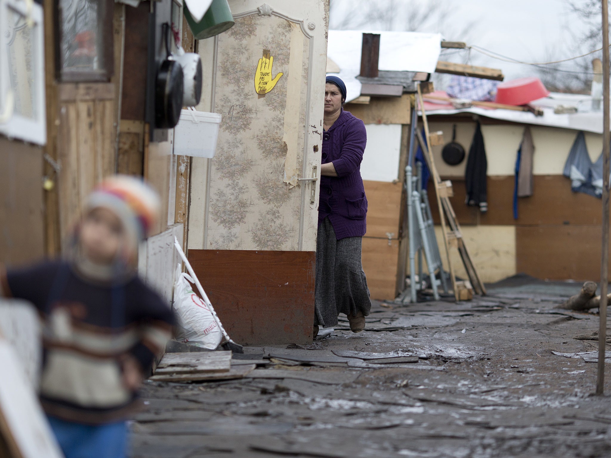 A woman from the Roma community works at the entrance of her shack in a camp in Stains, outside Paris