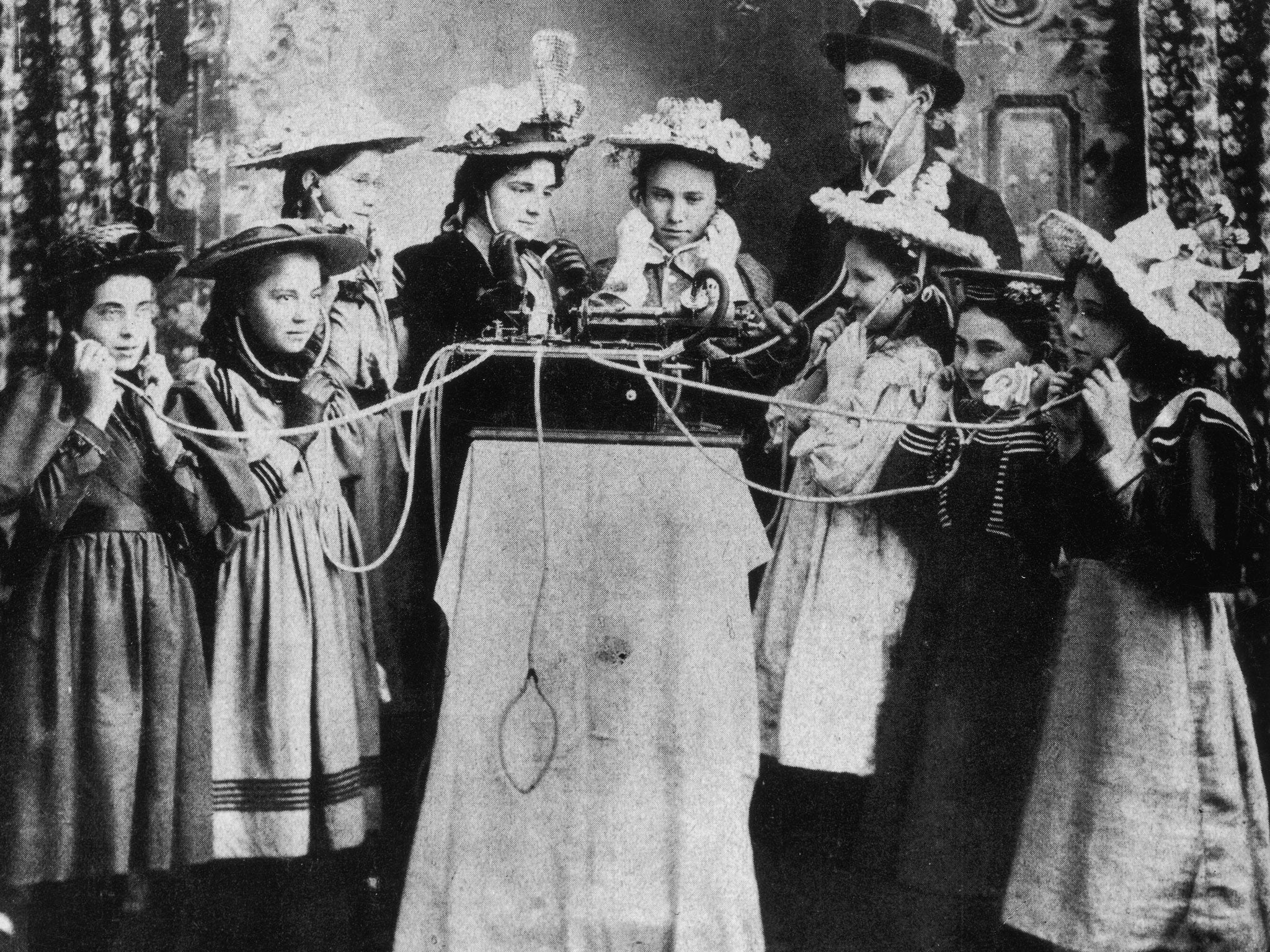 A group of people listen to a jukebox in Salina, Kansas circa 1890