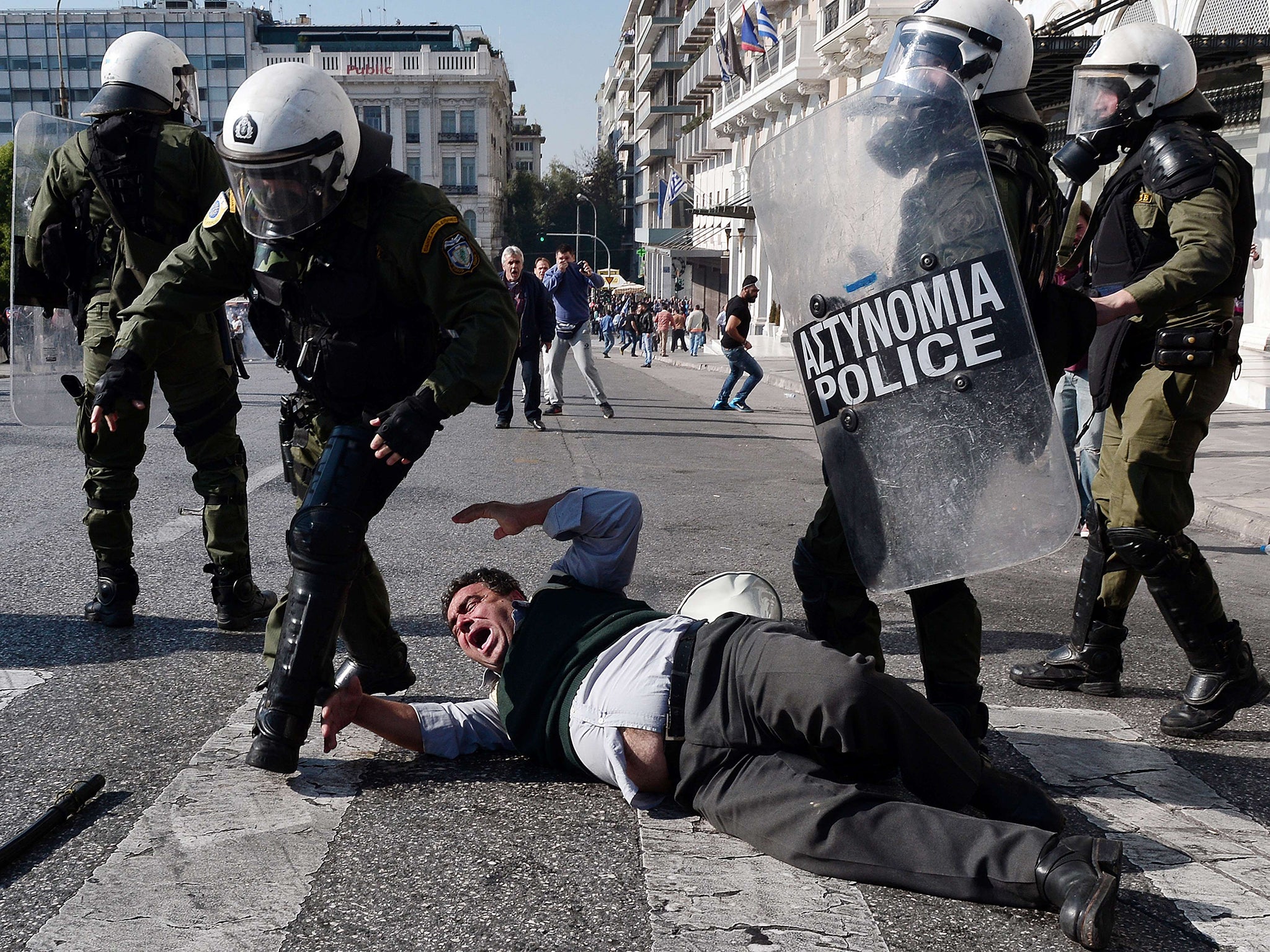 Greek riot police officers scuffle with a protester during a demonstration