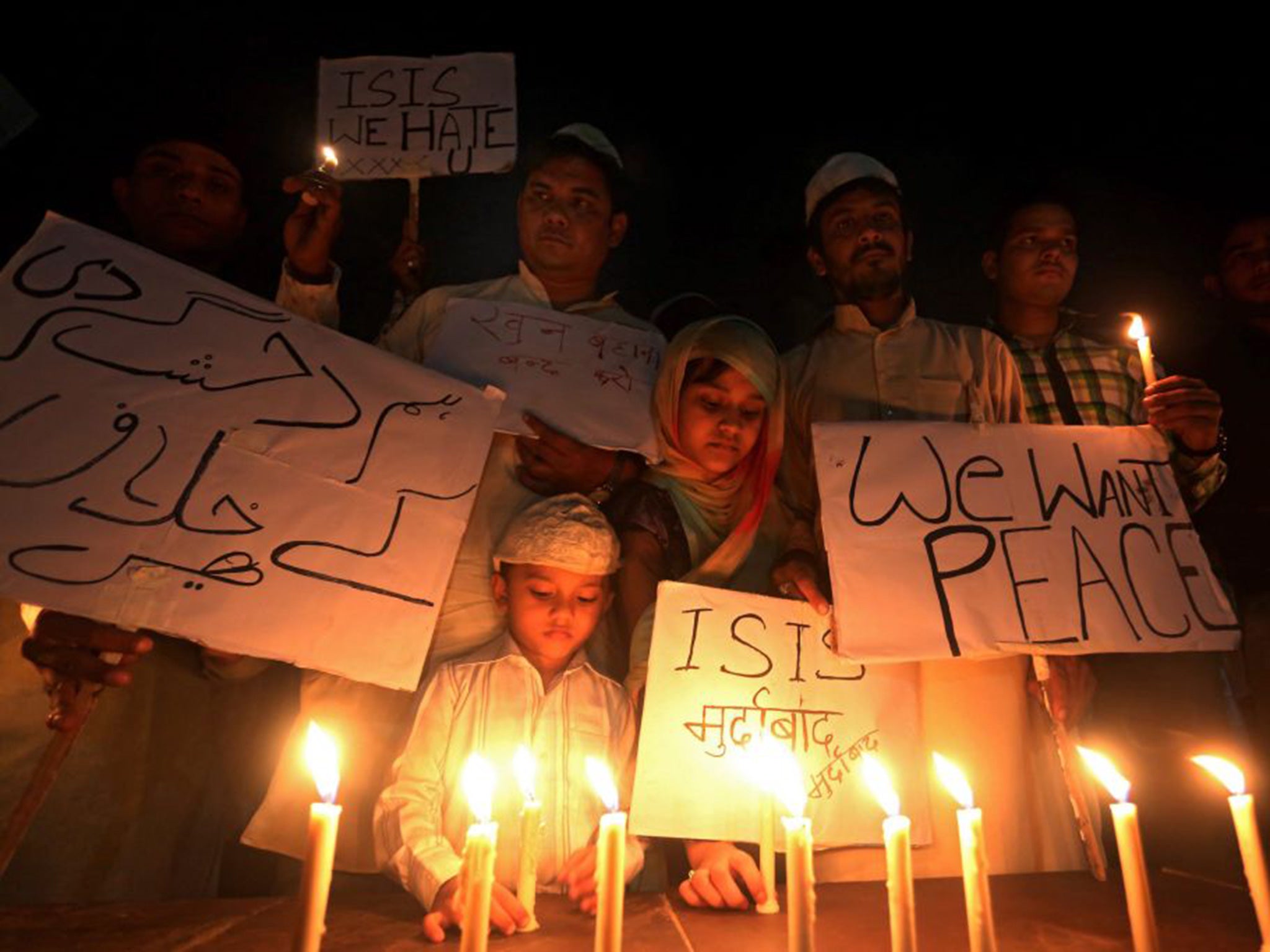 Indian Muslims and children hold candles and slogans against ISIS as they organize a candle light vigil for the victims of the deadly terrorist Paris attacks in Bhopal, India