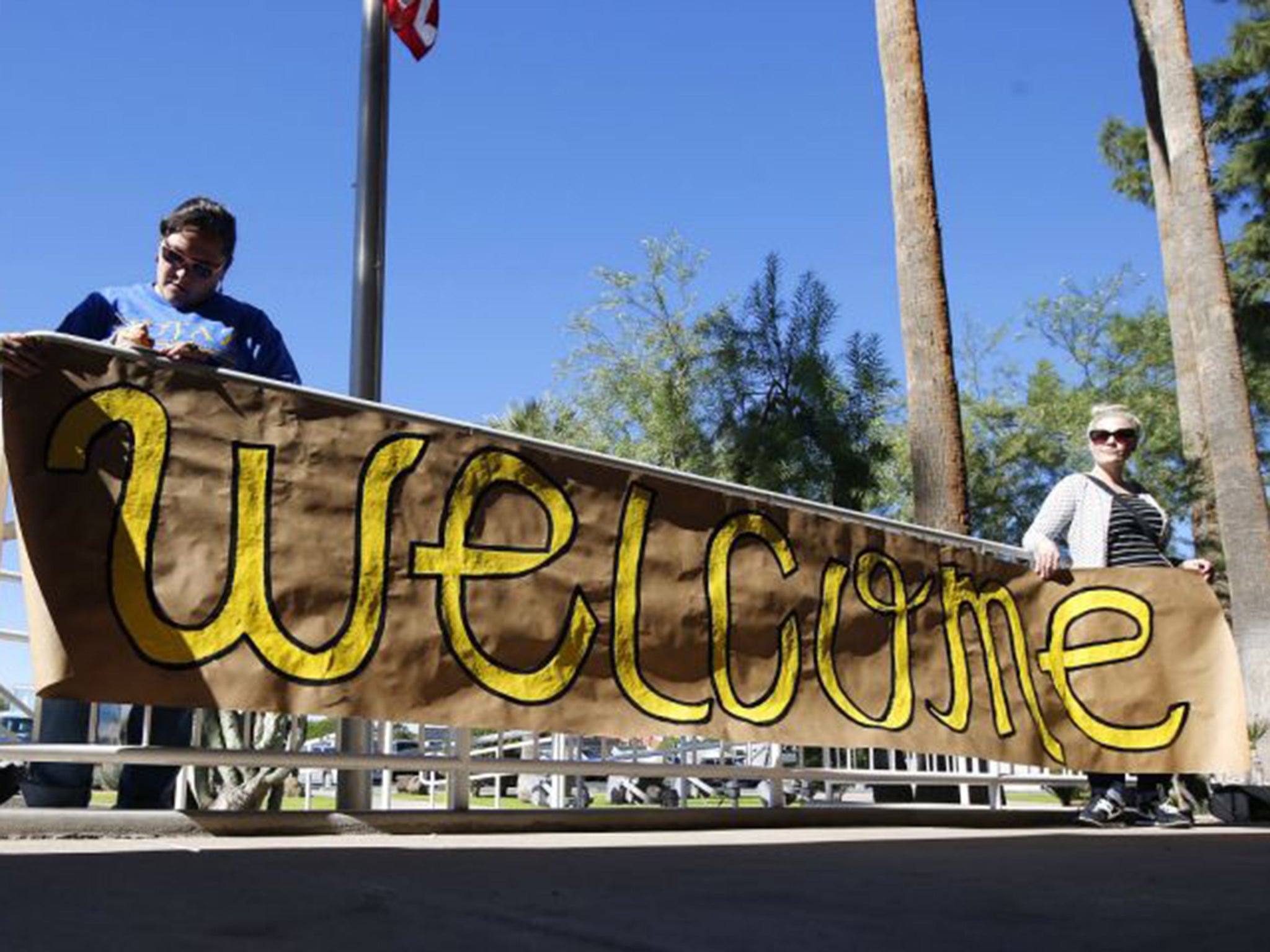 Supporters place a sign welcoming Syrian refugees is placed at the entrance to the office of Arizona's governor