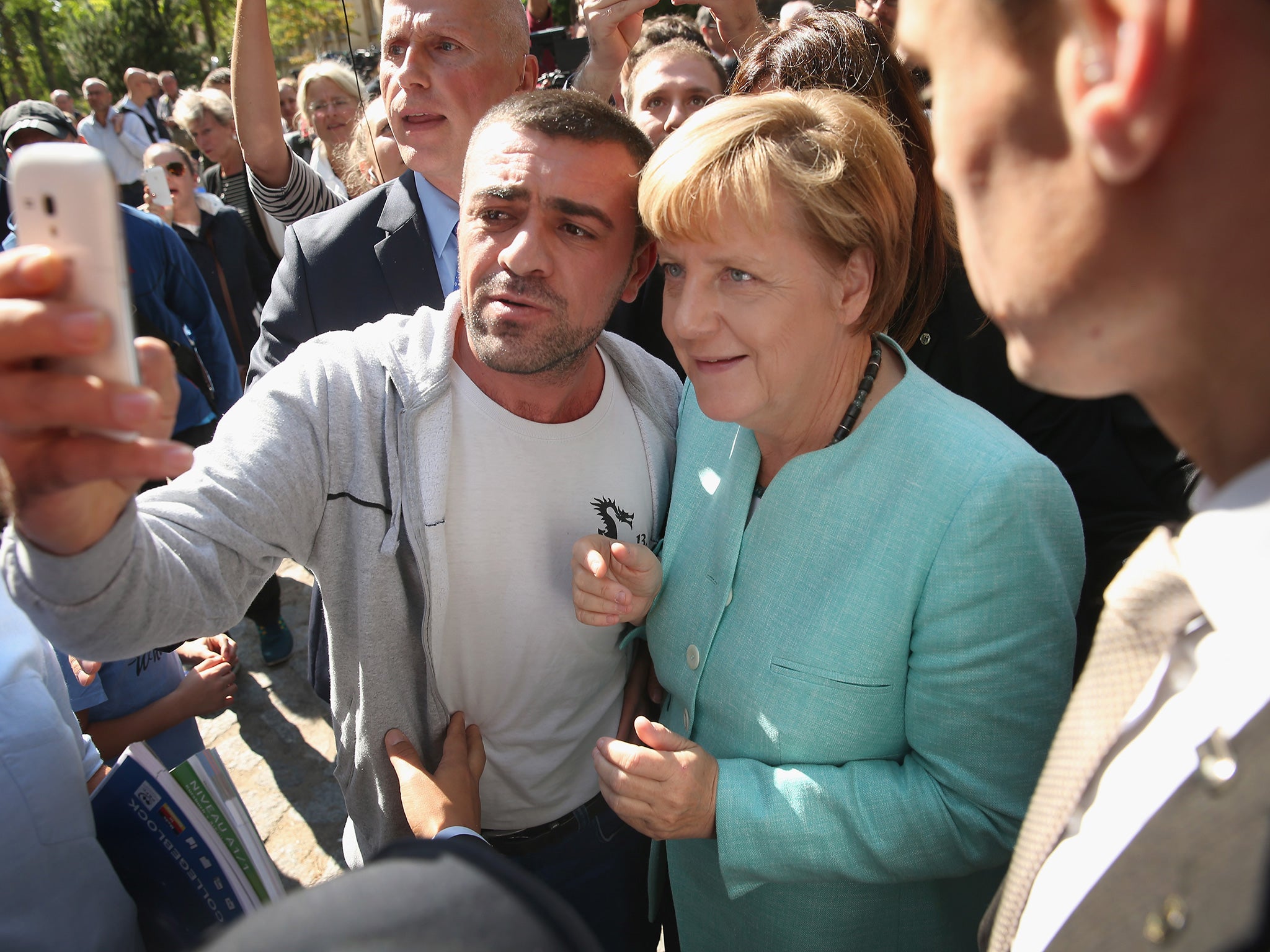 Angela Merkel poses for a selfie with a refugee after visiting a shelter for migrants in Berlin