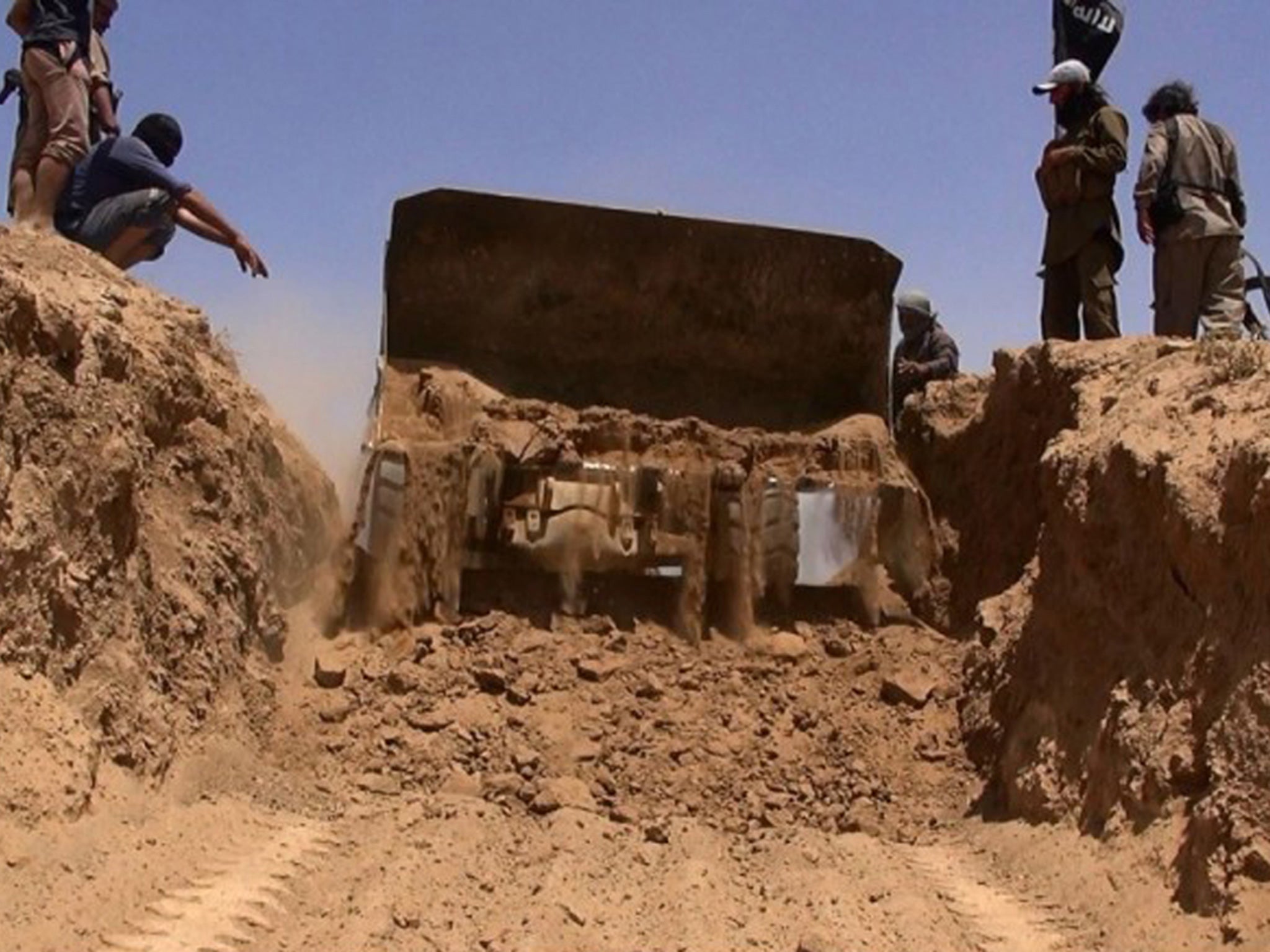 A bulldozer cuts through a sand rampart at the Syrian border in the early Isis video