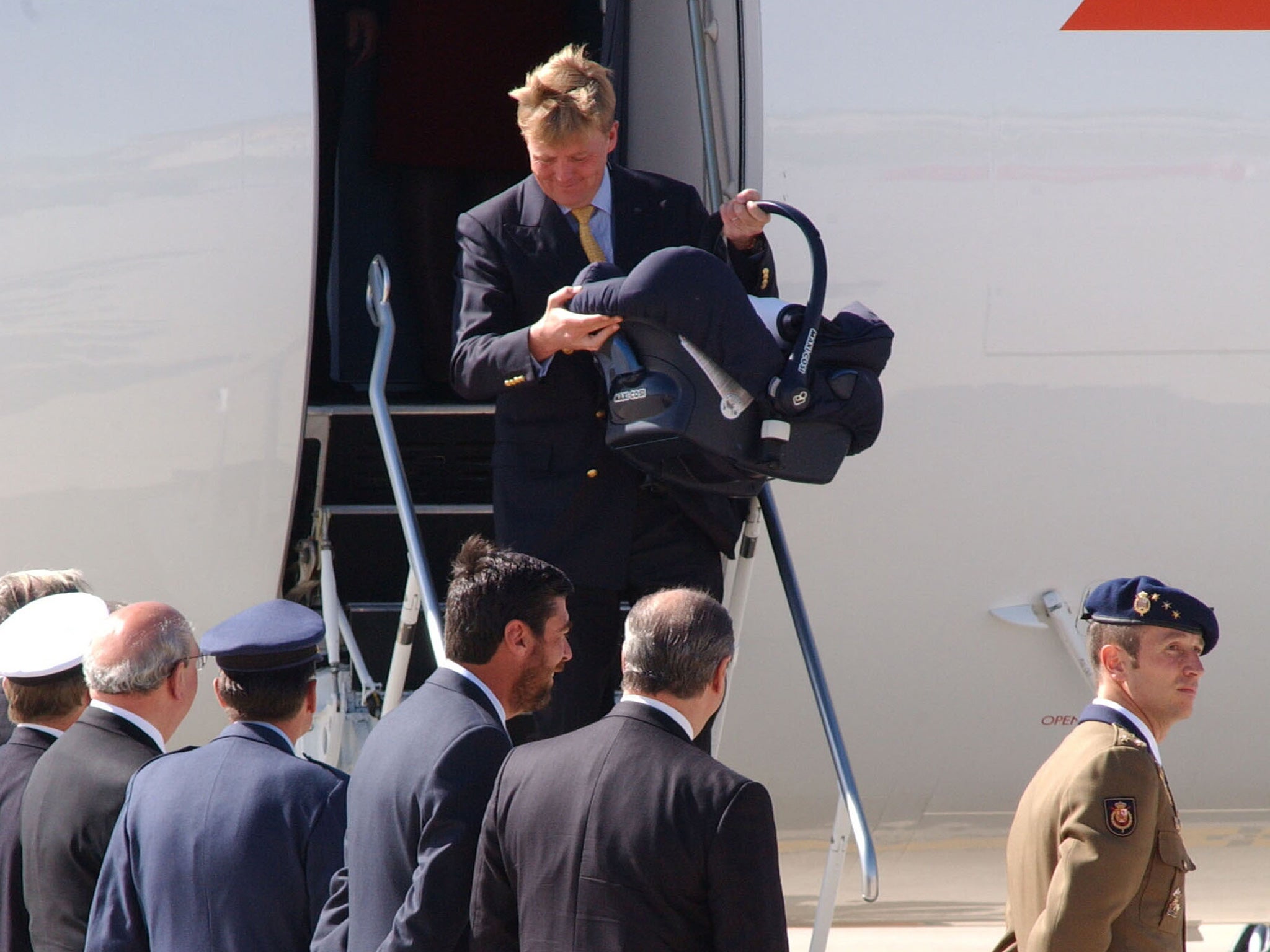 King Willem-Alexander of the Netherlands carries his daughter as he disembarks at Madrid airport