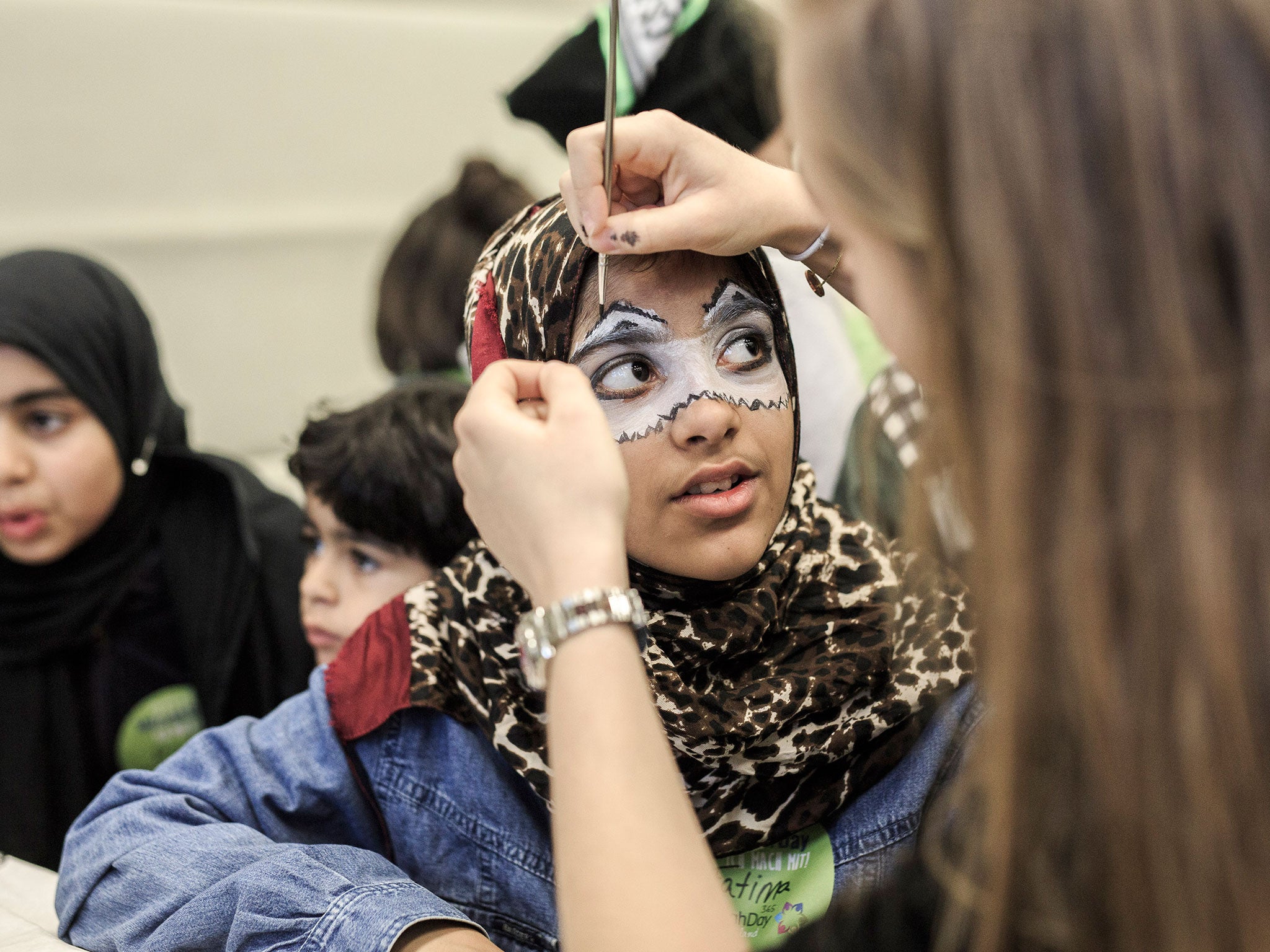 A volunteer paints the face of a girl at a shelter for refugees and migrants on Mitzvah Day in Berlin last weekend (Getty)