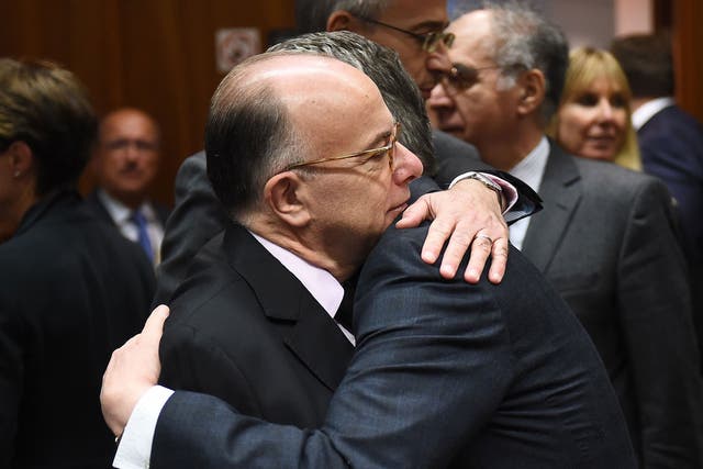 German Interior Minister Thomas de Maiziere (R) embraces French Interior Minister Bernard Cazeneuve during a meeting at the European Council in Brussels on 20 November
