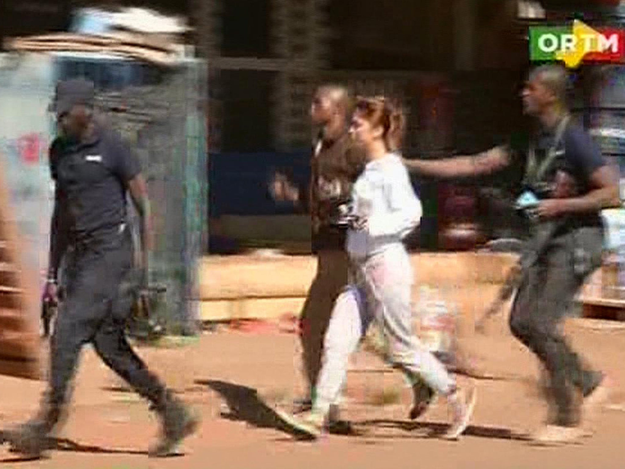 A woman is led away by security personnel from the Radisson Blu Hotel hotel in Bamako