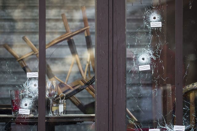 Bullet holes are seen in the terrace windows of Cafe Bonne Biere, as people lay flowers and candles in front, in Paris, France, 15 November 2015.