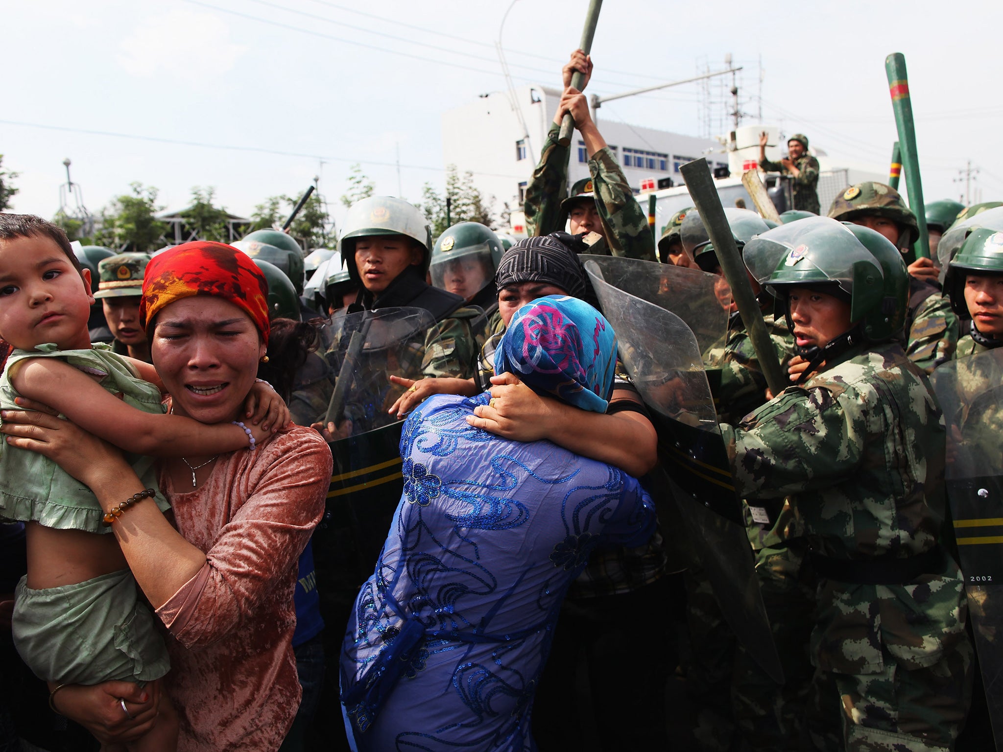 Chinese policemen push Uighur women during a 2009 protest