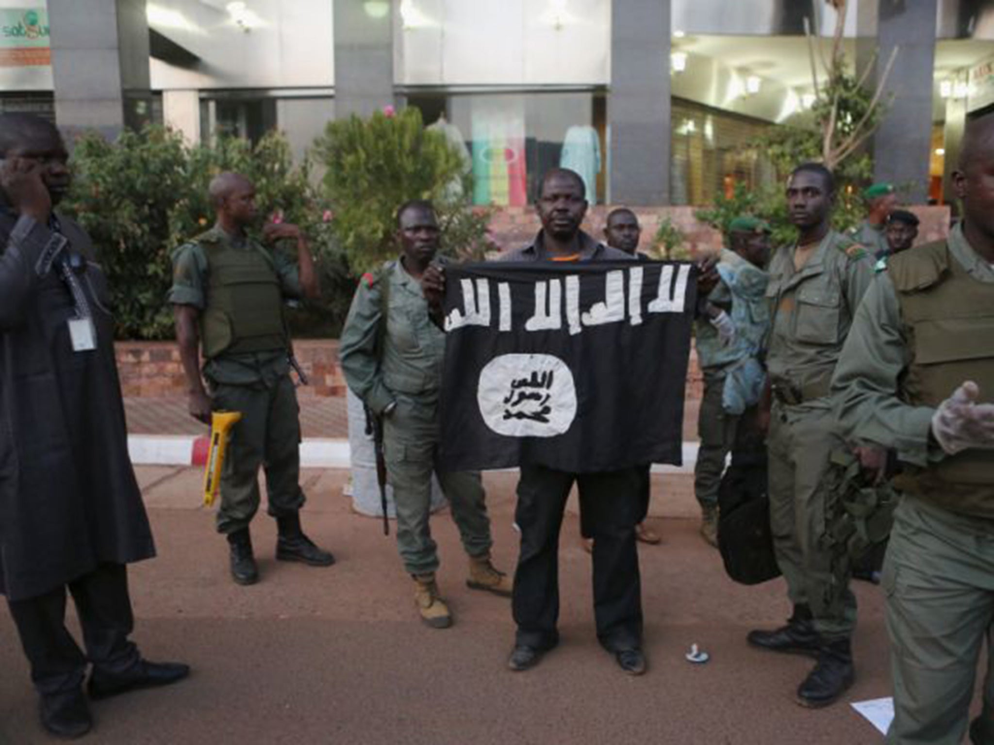 Malian security officials show a jihadist flag they said belonged to attackers in front of the Radisson hotel in Bamako