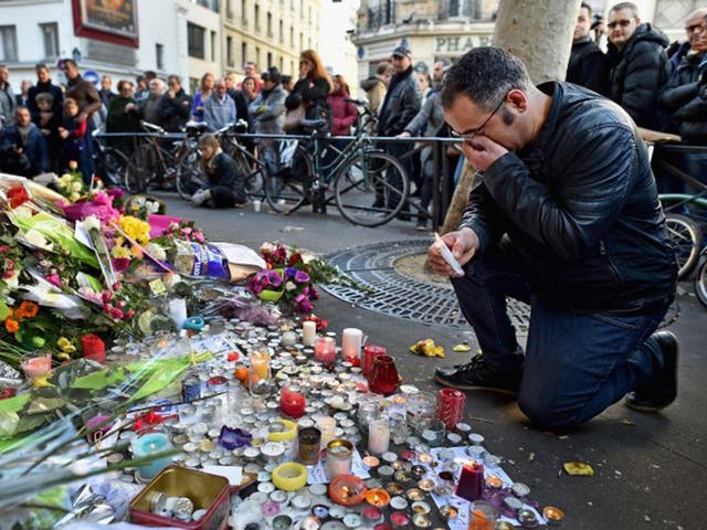 Members of the public gather to lay flowers and light candles at La Belle Equipe