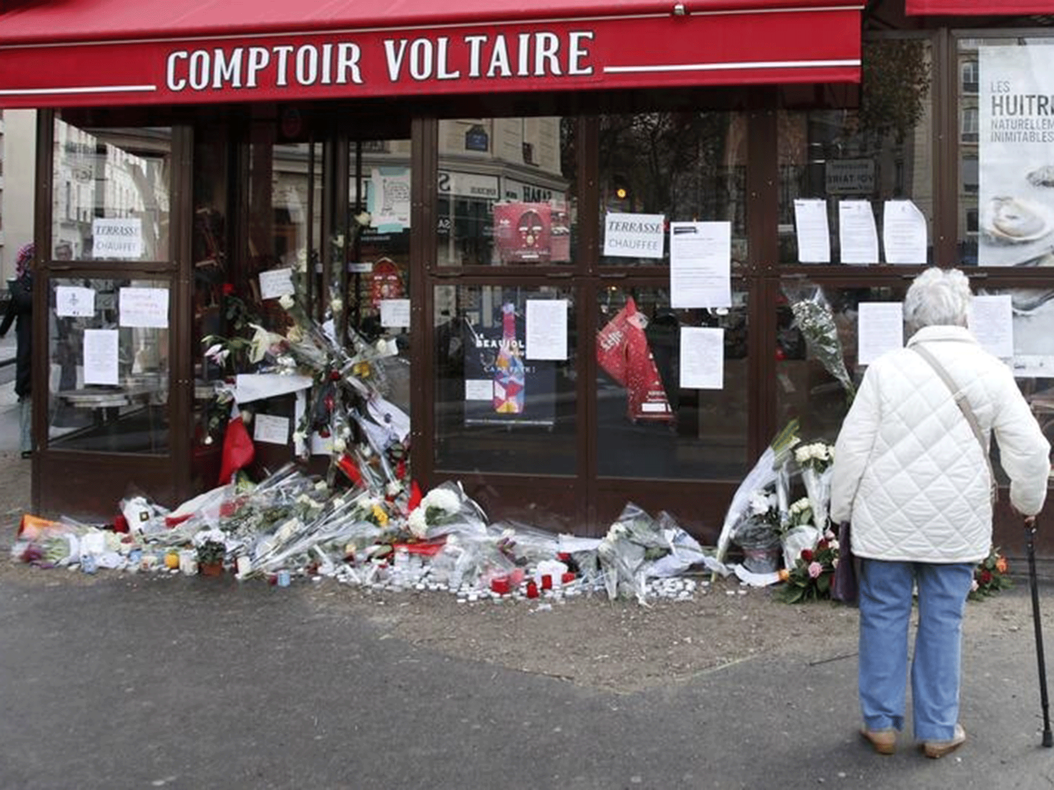 A woman stops to look at flowers, candles and messages in tribute to victims in front of the Comptoir Voltaire cafe, one of the sites of the deadly attacks in Paris, France, November 17, 2015.