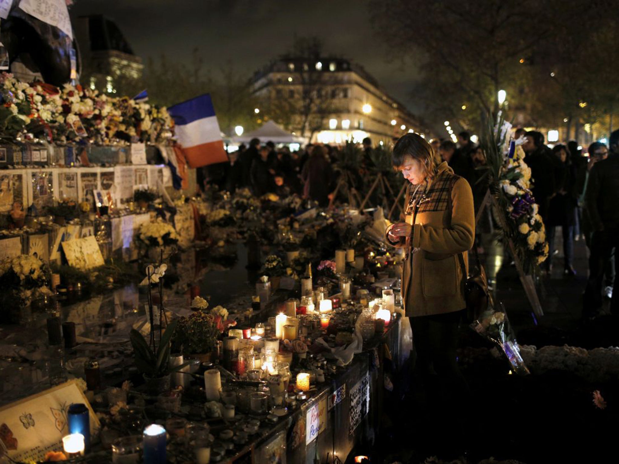 A woman lights an candle in the Place de la République