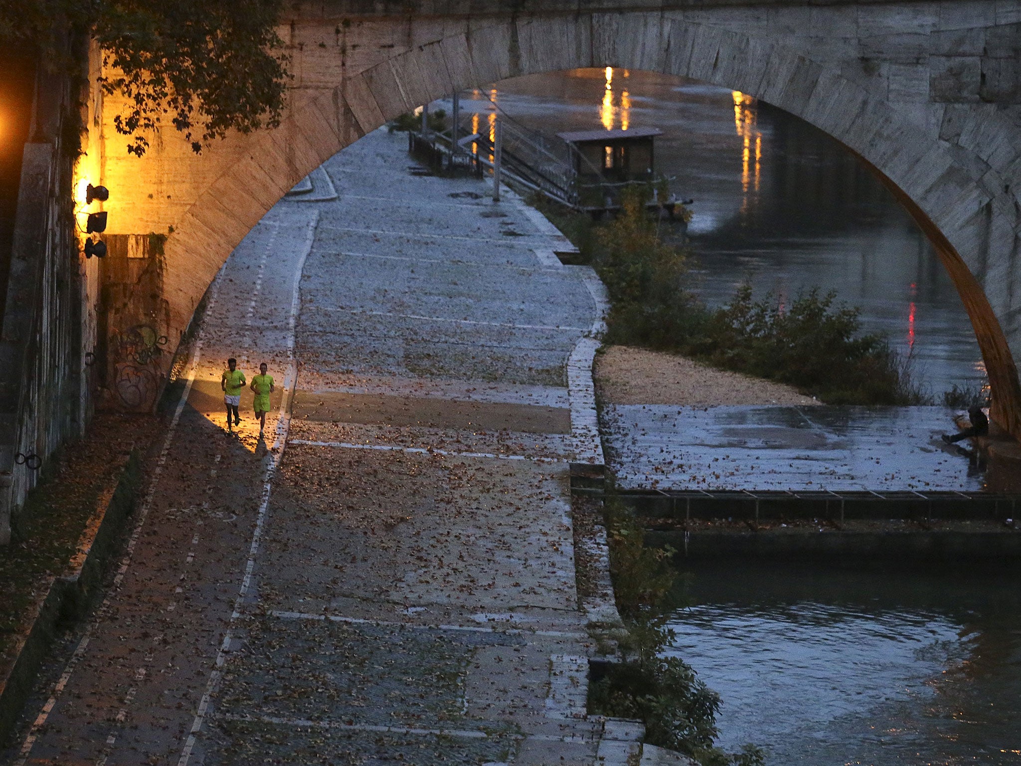 Men jog along the Tiber river in downtown Rome, Italy