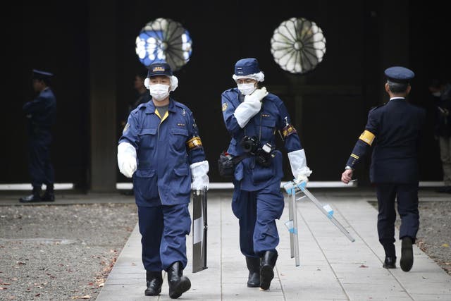 Police officers investigate the compound of the Yasukuni shrine