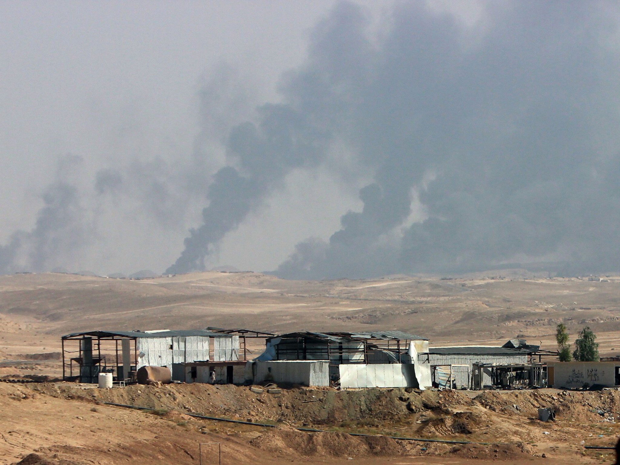 Smoke rises as Iraqi security forces and allied Popular Mobilization Forces shell Islamic State group positions at an oil field outside Beiji, Iraq, in October 2015.