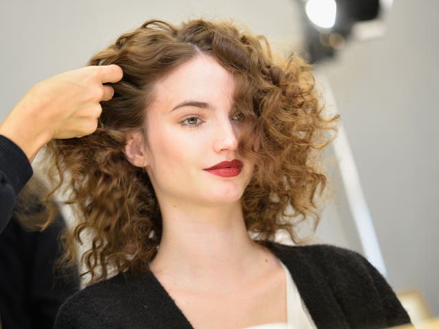 A hairdresser styles a woman's hair