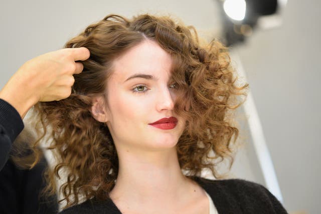 A hairdresser styles a woman's hair