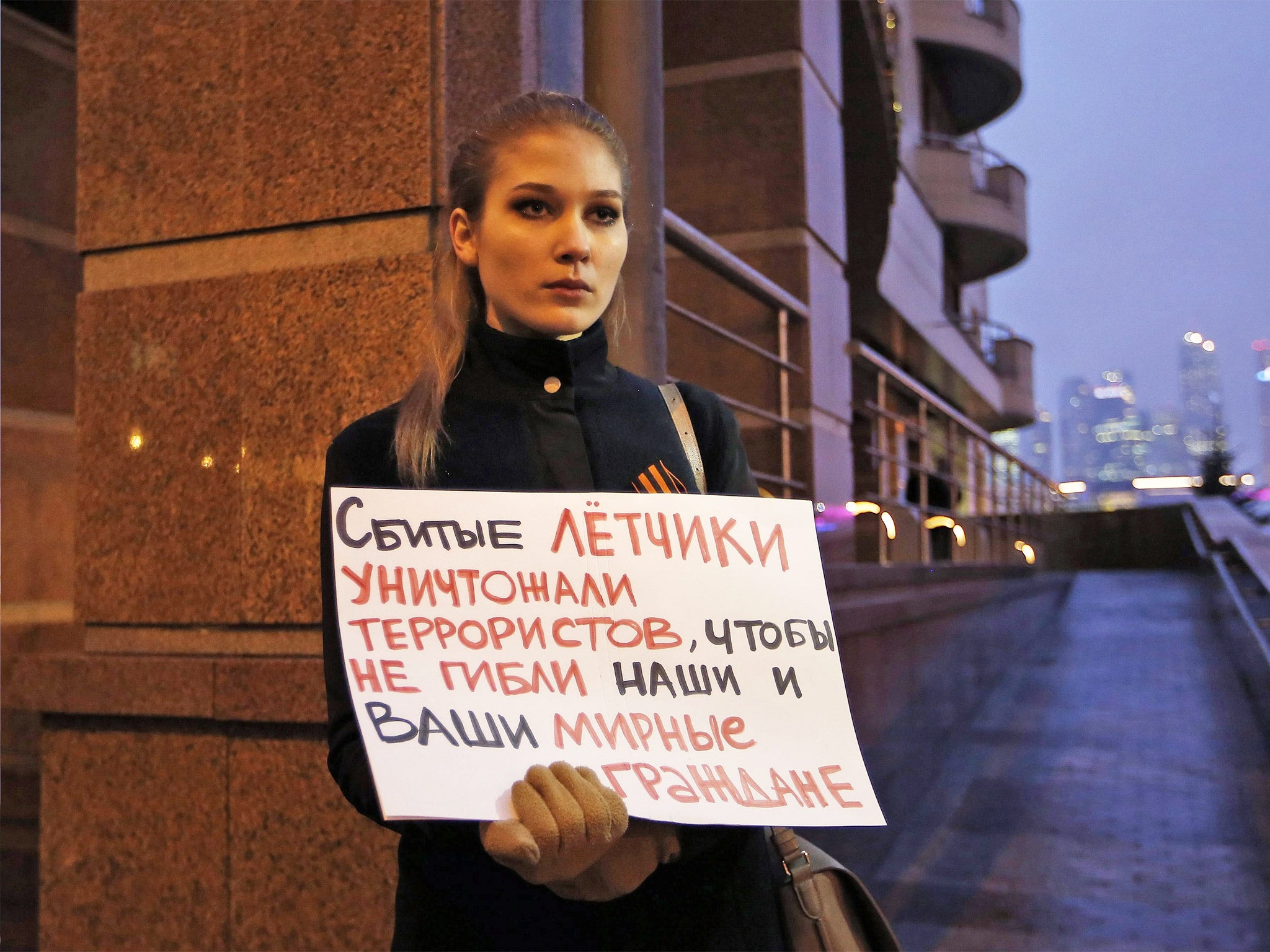 A woman holds a poster saying 'The hit pilots have been destroying terrorists to save lives of our and your civilians' while picketing the Turkish Embassy in Moscow, Russia, on Tuesday