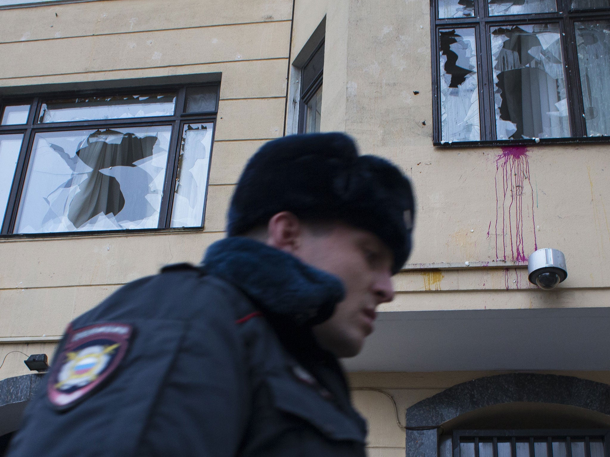 A policeman walks past the Turkish Embassy with broken window planes in Moscow, Russia, on Wednesday, Nov. 25, 2015.