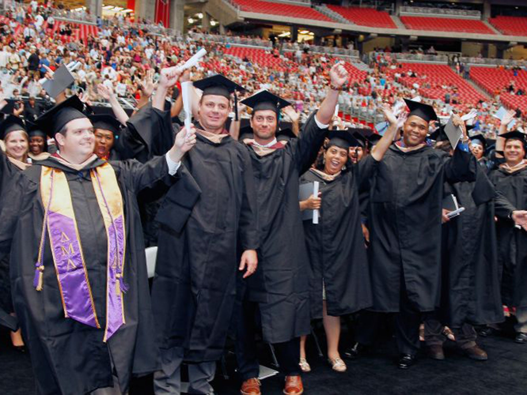 Students show their excitement during the graduation ceremony for the University of Phoenix at the Arizona Cardinals stadium