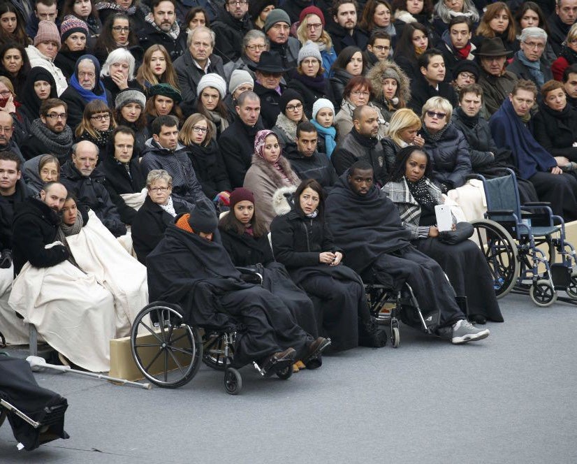 Wheelchair-bound victims sit with the relatives of the 130 killed in the Paris attacks