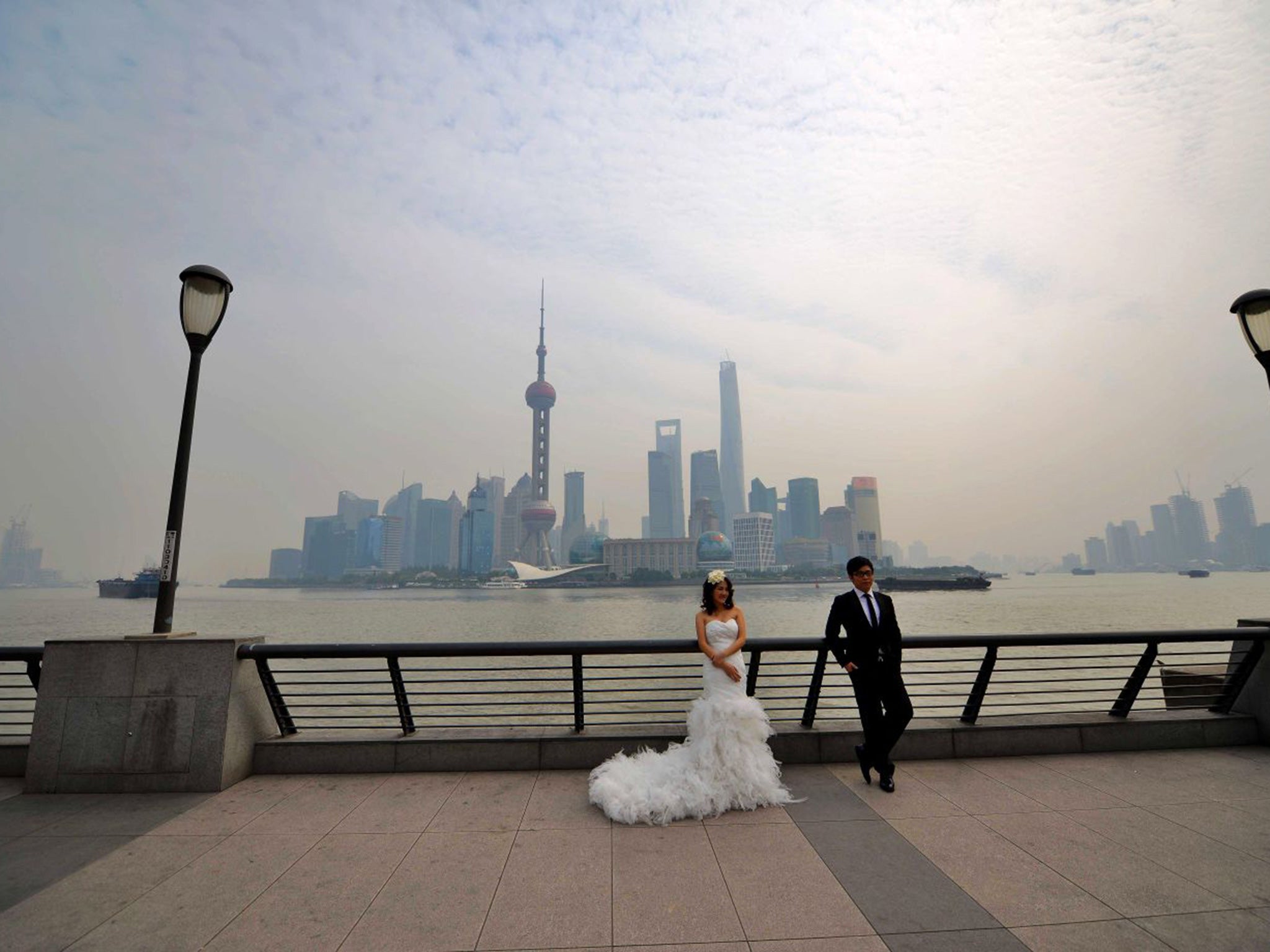 A recently married couple take wedding photos in front of Shaghai's business district