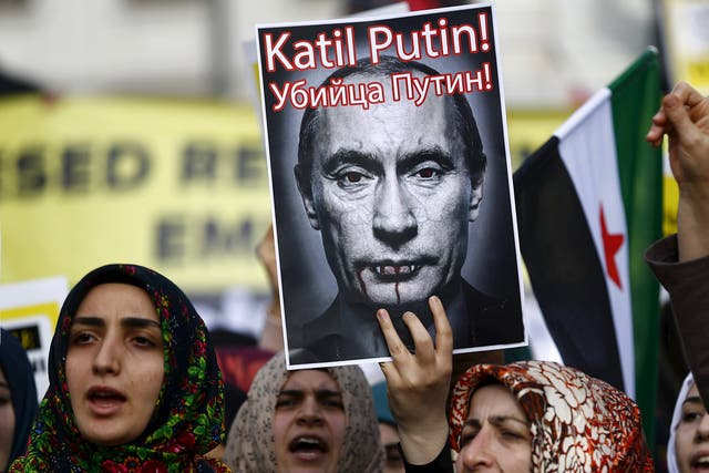 Demonstrators hold a defaced poster of Vladimir Putin – branded ‘a killer’ – at an anti-Russian protest in Istanbul yesterday