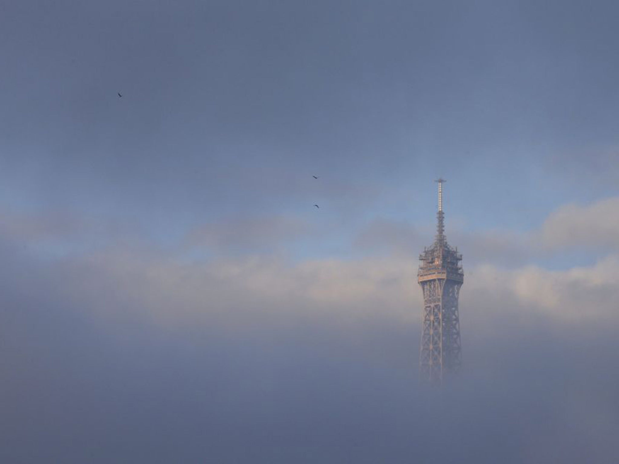 The Eiffel Tower is partially covered by an early morning fog in Paris, France, November 27, 2015 as the capital will host the World Climate Change Conference 2015 (COP21) from November 30 to December 11