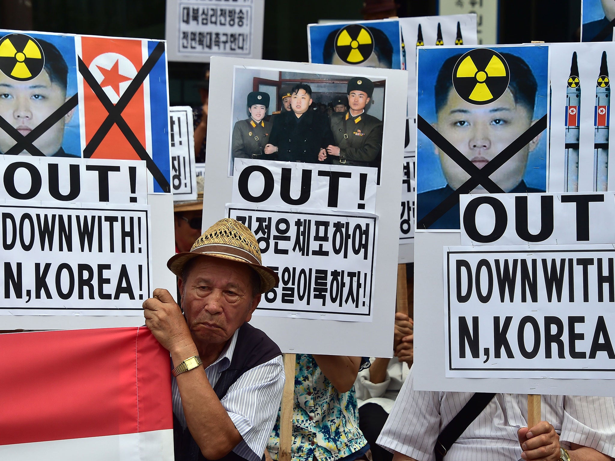 South Korean activists hold placards showing portraits of North Korean leader Kim Jong-Un during a rally denouncing North Korea's rocket firing, in Seoul on 21 August, 2015