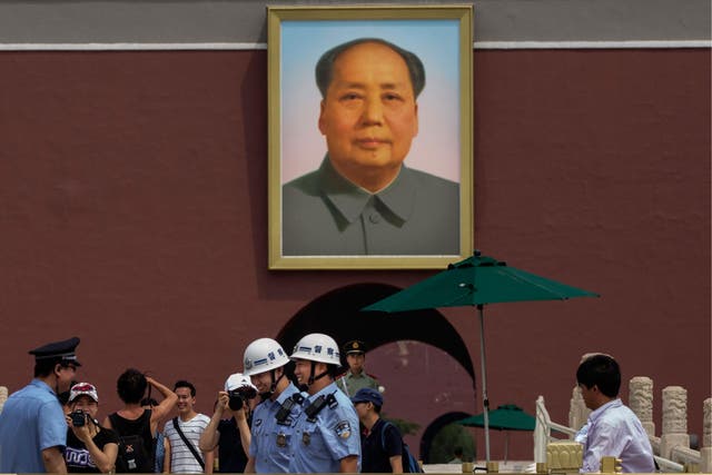 Chinese police and tourists stand underneath a picture of late leader Mao Zedong outside the Forbidden City in Tiananmen Square