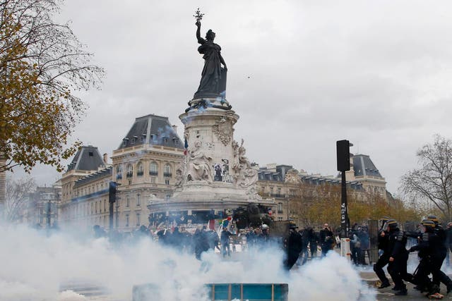 Clouds of tear gas fill the air as demonstrators clash with French CRS riot police at the Place de la Republique after the cancellation of the planned climate march