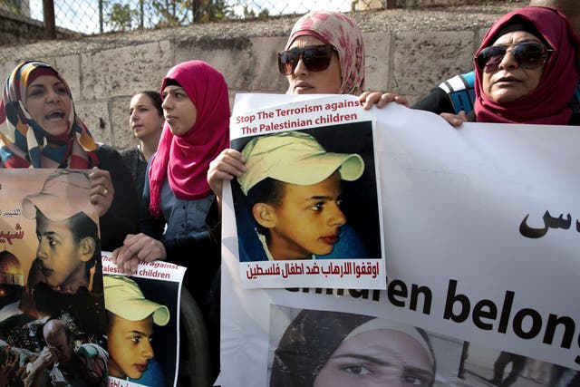 Protesters hold posters of Palestinian teenager Mohammed Abu Khdeir, who was killed last year, outside the district court in Jerusalem on November 30, 2015