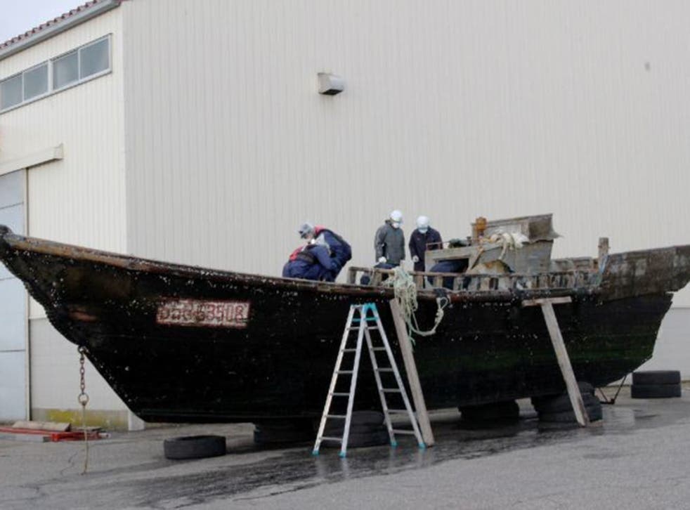 Coast guard officials investigating a wooden boat at the Fukui port, western Japan after the ship was found drifting off the coast of Fukui