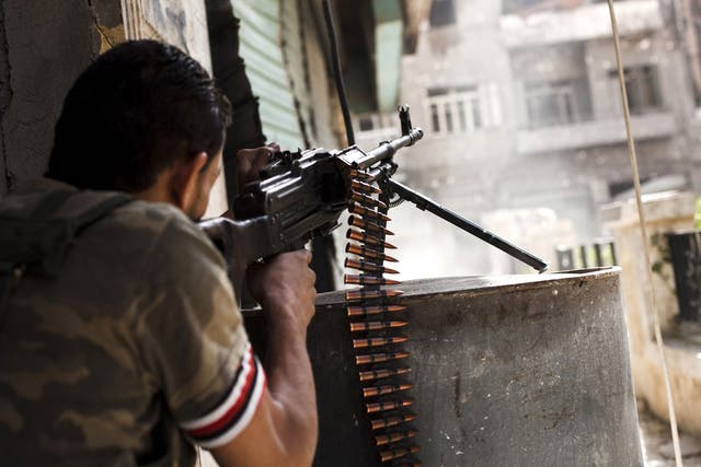 File: A rebel fighter fires his gun against a Syrian government troop position in the Bustan al-Basha area of the northern Syrian city of Aleppo