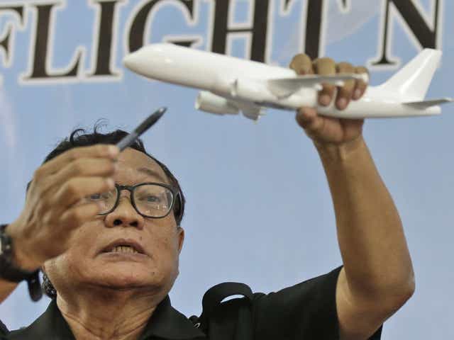 Indonesian National Transportation Safety Committee Chief Investigator Marjono Siswosuwarno holds up a model plane as he explains the movement of AirAsia Flight QZ8501, at a news conference in Jakarta on Tuesday