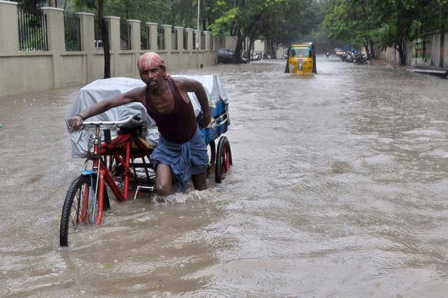 An Indian labourer pushes his cycle trishaw through floodwaters in Chennai during a downpour of heavy rain
