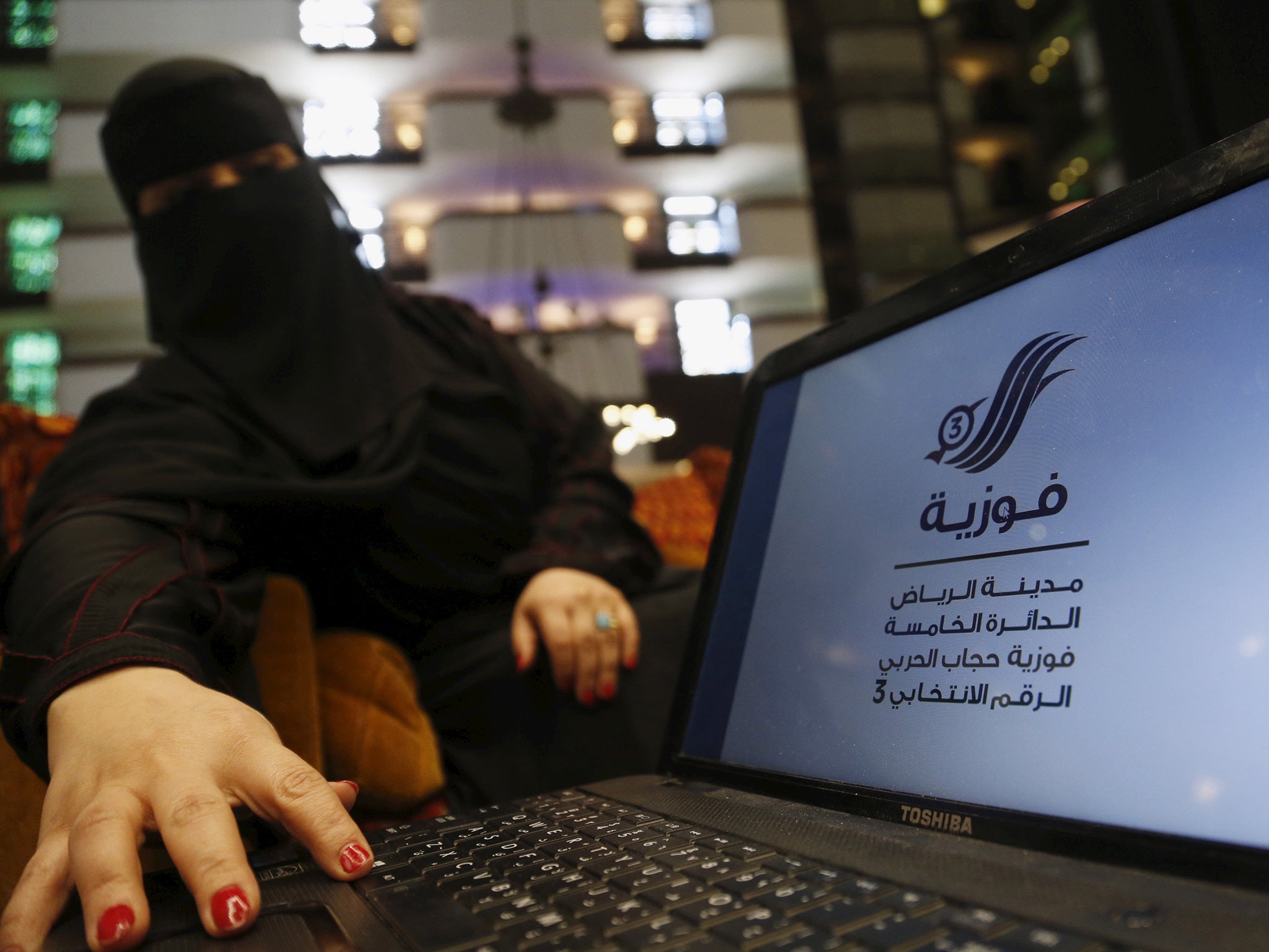 Saudi woman Fawzia al-Harbi, a candidate for local municipal council elections, shows her candidate biography at a shopping mall in Riyadh
