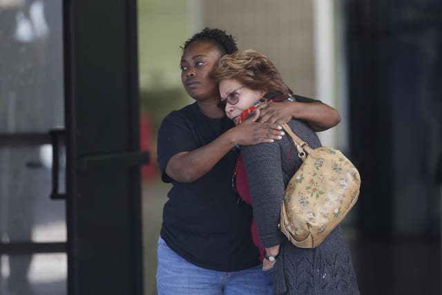 Two women embrace at a community center where family members gathered to pick up survivors in San Bernardino.