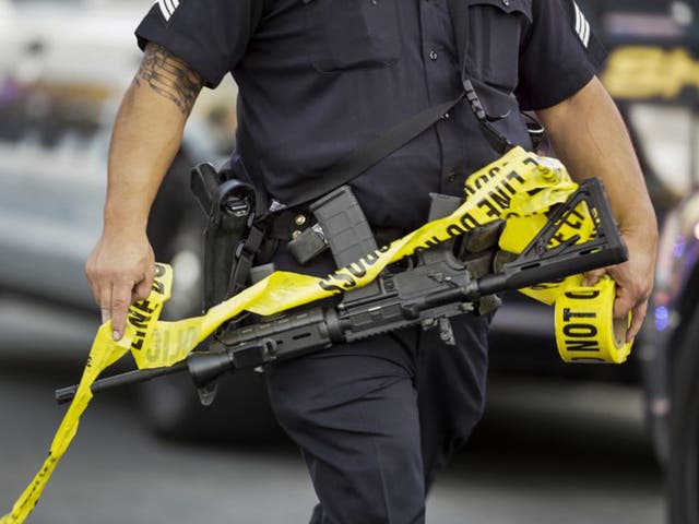 A police officer deploys tape to an area near to scene of the massacere by two attackers in San Bernardino, California